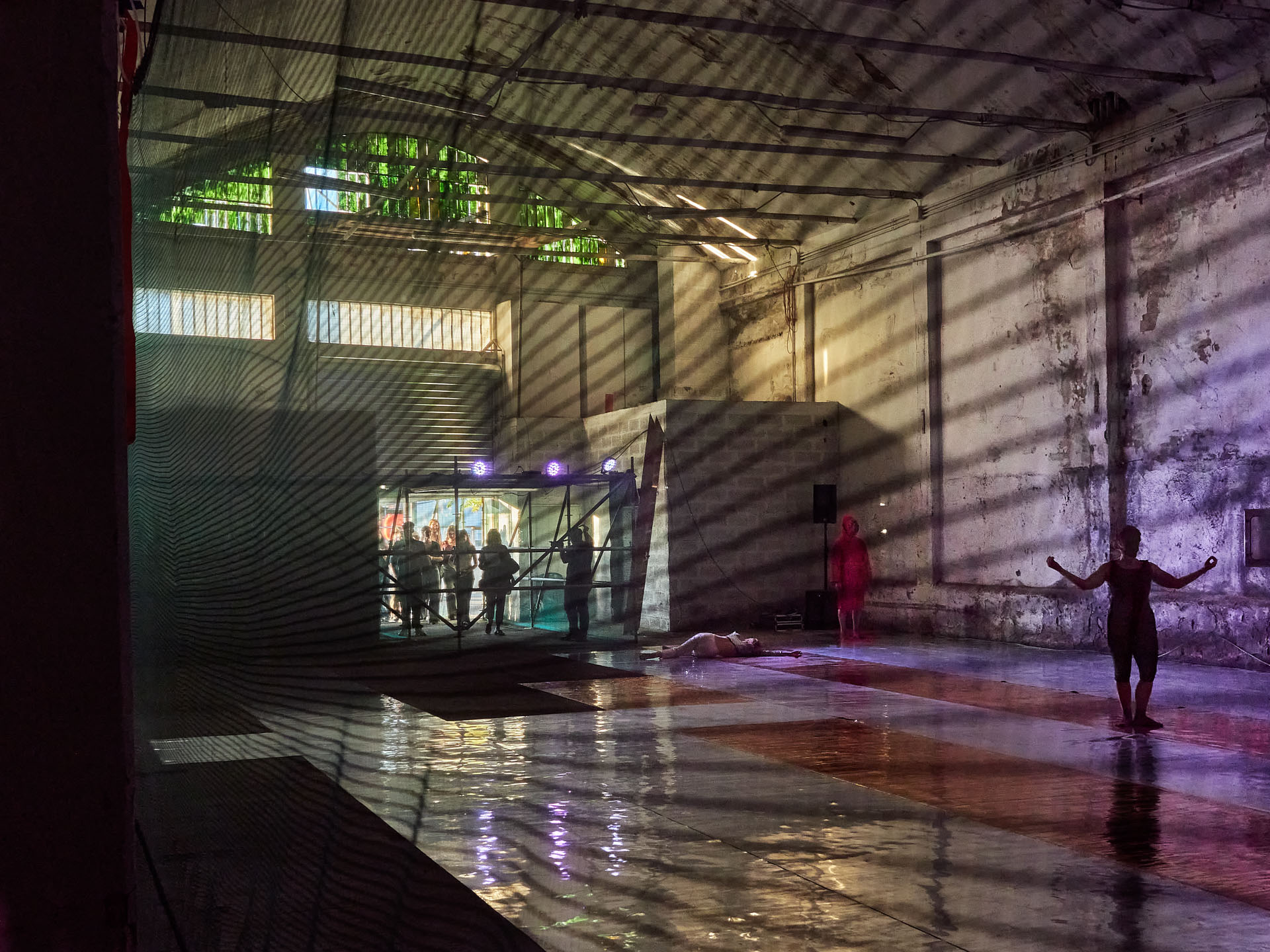 gruppo nanou – Specie di spazi. Foto: Daniele Casadio Sala con pannelli sospesi, pubblico e fotografi sul pavimento specchiante, una silhouette in primo piano
